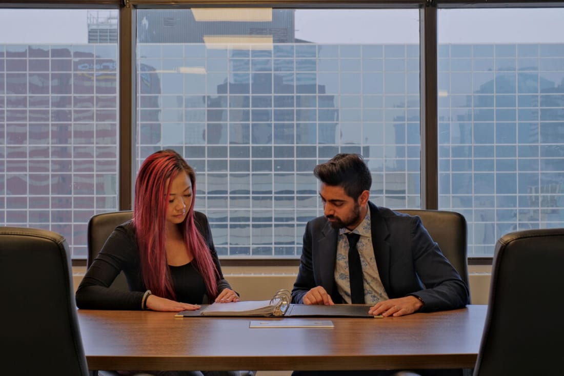 A Bhardwaj + Co. lawyer reviewing documents with a client overlooking downtown Edmonton